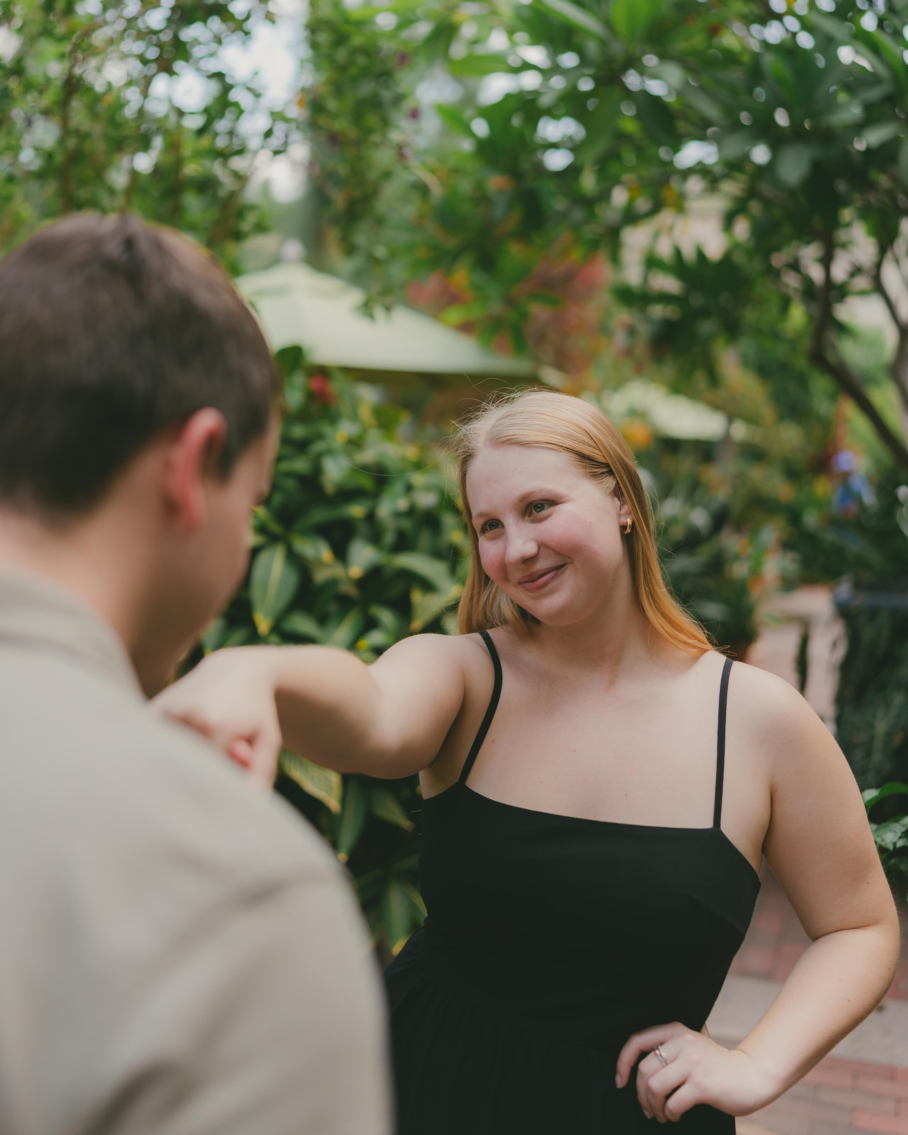 a man with his back to the camera holding a girl's handw who's smiling